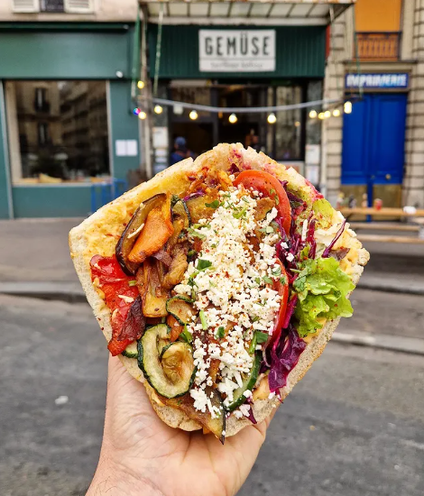 Main tenant un kebap Gemüse devant le restaurant